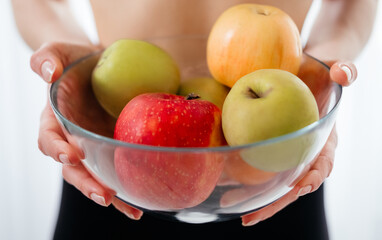 Organic food. Sportive woman. Keep diet. Fitness nutrition. Slim body. Vitamins balance. Unrecognizable lady in sportswear holding bowl with fresh apples closeup.