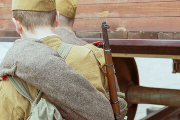 Soldiers of the Red Army during the Second World War stand near a railway carriage. Rifles and military clothing. View from the back. Vintage style.