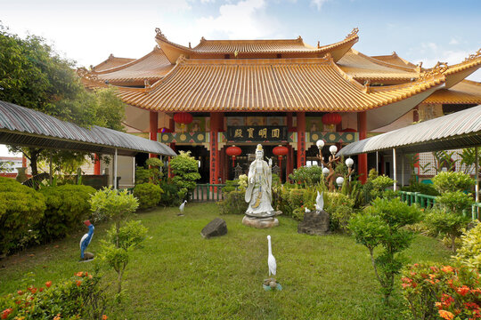 Statuary decorates a lush garden in front of the tile-roofed Toh Tze (Poh Toh Tse, Pu Tuo Si) Chinese Buddhist temple, Kota Kinabalu, Sabah (Borneo), Malaysia