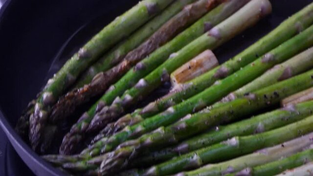 Seasonal asparagus frying in a pan with olive oil 