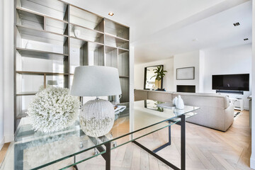 Spacious study room with futuristic glass table and armchair against window in modern apartment