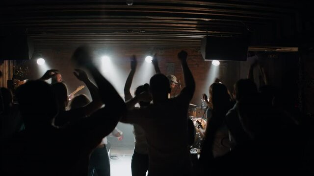 WIDE DOLLY Punk rock band playing music during their concert on a stage of crowded venue. Vocals, guitars and drums. Shot with 2x anamorphic lens