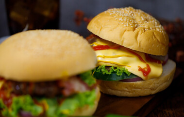 Ready to eat homemade hamburger with glass of drink in background. Taken with dark style light