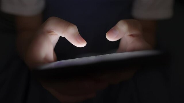 Hand of little girl using smartphone at night, typing message or chat