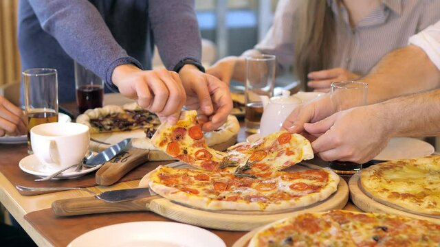 A young group of friends socialize, eat pizza, colleagues hang out in a cafe