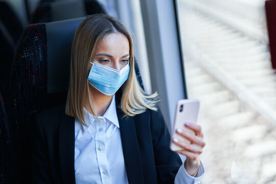 Subway Commuter Businesswoman In Mask On Public Transport Using Smartphone