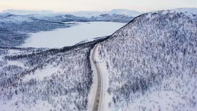 Aerial view of a truck driving on a polar road, in Lappland - descending, drone shot