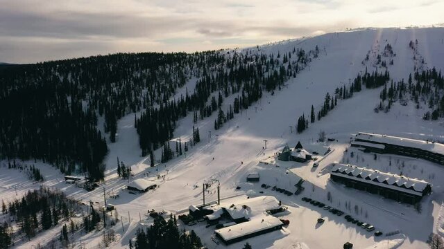 Aerial view of the Olos Ski Resort, in sunny spring Lapland - reverse drone shot