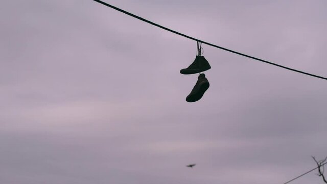 Old Shoes Hanging from power line by the laces.