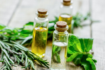natural cosmetic oil with fresh rosemary and mint on light wooden table background