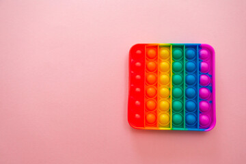 Colorful antistress pop it toy on the pink background.