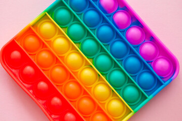 Colorful antistress pop it toy on the pink background.