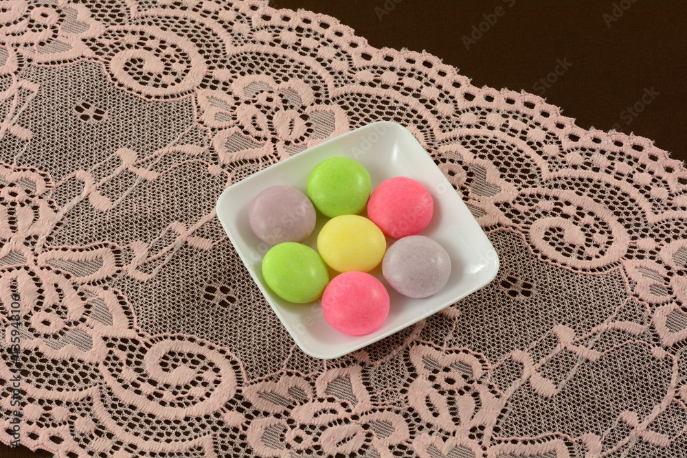 Wall mural multicolor soda pop mint candies small white candy dish on pink lace table runner on brown tableclot