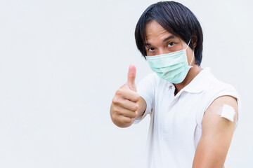 asian man get vaccinated of covid-19 and show his thumb up sign.