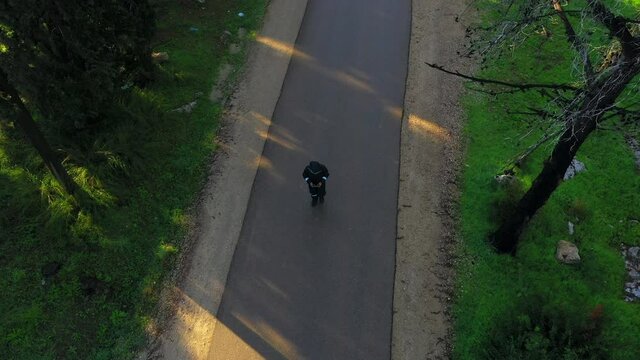 Aerial Upward Shot Of Person Walking On Road Amidst Tress, Drone Flying Over Vehicles During Day - Ben Shemen, Israel