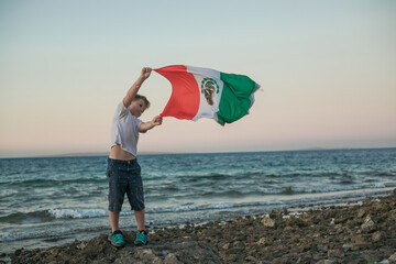 Young boy holding flag of Mexico at the Sea