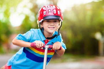 Fototapeta na wymiar Little boy riding scooter. Kids ride kick board.