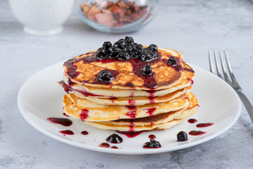 Small pancakes with blueberry jam for breakfast on the kitchen table.