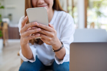Closeup image of a beautiful young asian woman holding and using mobile phone