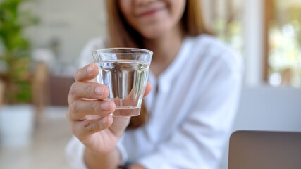 Closeup image of a woman holding a glass of water to drink