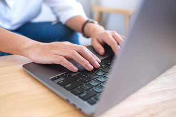 Closeup image of a woman working and typing on laptop computer keyboard on the table