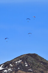 Fototapeta na wymiar Outdoors enthusiasts enjoy a day of paragliding in the mountains near Eagle River, Alaska.
