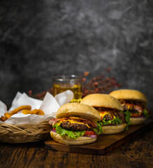 Beef hamburgers with fried onions, spinach, ketchup, pepper and cheeseserved on a wooden board with beer in loft background with copy space