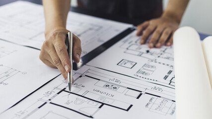 Engineer and Architect concept, Man uses a ruler to measure the floor plan on the blueprint, Building architecture design work, Construction design project under environmental conservation conditions. © Puwasit Inyavileart