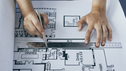 Engineer and Architect concept, Man uses a ruler to measure the floor plan on the blueprint,...