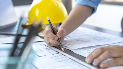 Engineer and Architect concept, Man uses a ruler to measure the floor plan on the blueprint, Building architecture design work, Construction design project under environmental conservation conditions.