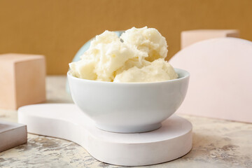 Bowl with shea butter on color background