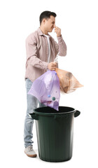 Young man throwing garbage in trash bin on white background