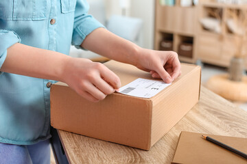 Young woman preparing parcel for client at home, closeup