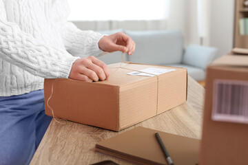 Young woman preparing parcel for client at home, closeup