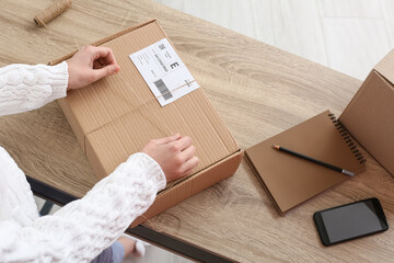 Young woman preparing parcel for client at home, closeup