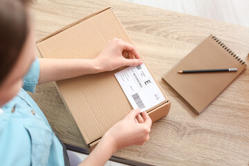 Young woman preparing parcel for client at home, closeup