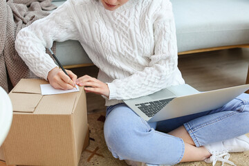 Young woman preparing parcel for client at home