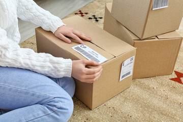 Young woman preparing parcel for client at home