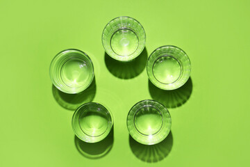 Glasses of water on color background