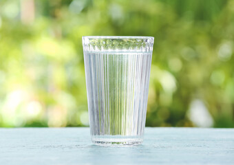 Glass of fresh cold water on table outdoors