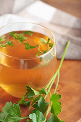 Cup of hot tea and parsley on wooden background, closeup