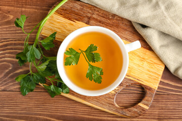 Cup of hot tea and parsley on wooden background