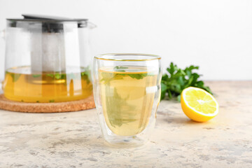 Teapot and cup of hot tea, parsley with lemon on light background