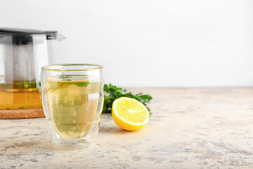 Fototapeta premium Herbal tea in double-walled glass with fresh lemon and parsley, healthy beverage
