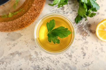 Cup of hot tea, parsley and lemon on light background
