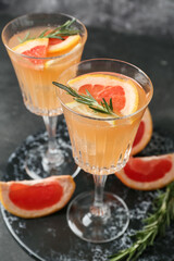 Glasses of tasty grapefruit cocktail with rosemary on dark background, closeup