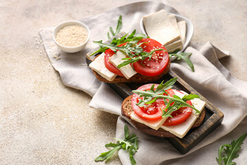 Fototapeta na wymiar Tasty bruschettas with tomato and tofu cheese on grunge background