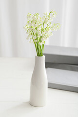 Vase with beautiful lily-of-the-valley flowers on table