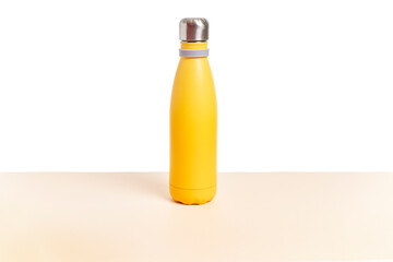 Reusable yellow steel bottle on a table and a white background