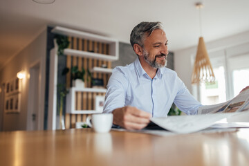Portrait of a happy man reading newspaper.